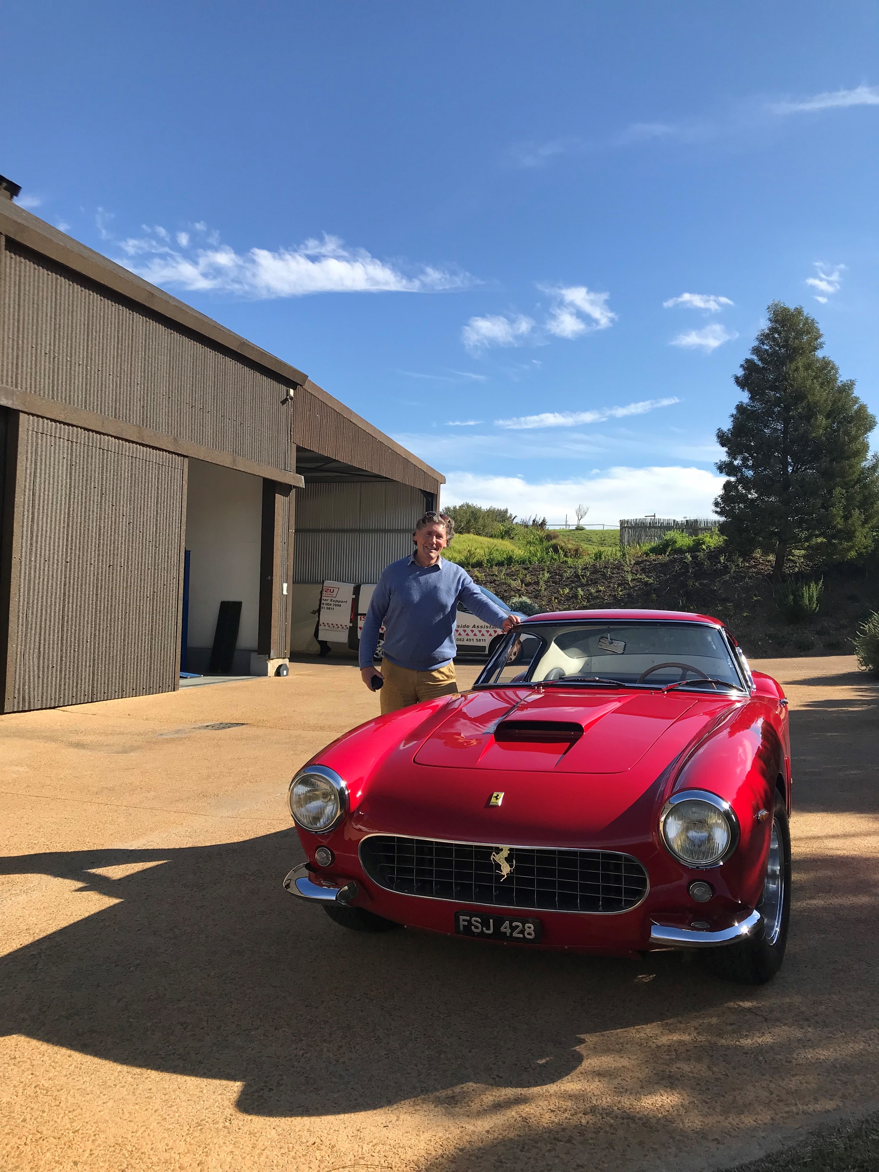 Iain Tyrrell standing next to a red Ferrari 250GT SWB.