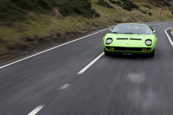 Green Lamborghini Miura driving on the road.