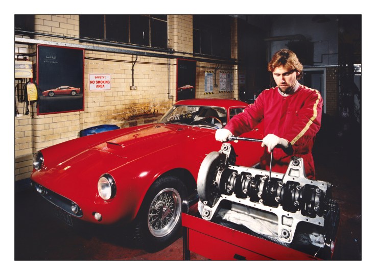 Iain Tyrrell working on a red Ferrari 205GT Tour de France v12 engine in 1995.